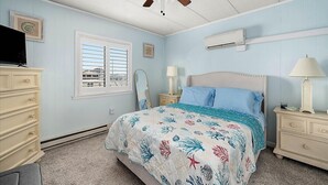Quarto com cama, cômoda, penteadeira e ventilador de teto.