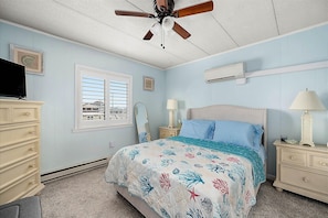 Ein Schlafzimmer mit Bett, Schminktisch, Kommode und Deckenventilator.