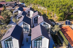 Un quartier résidentiel moderne composé de plusieurs maisons dotées de toits aux formes géométriques et de grandes fenêtres.