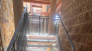 A staircase with metal railings, stone walls, and a view of the upper floor.