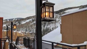 A snowy outdoor area with a metal railing, a wooden post, and a lantern.