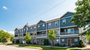 A multi-story residential building with balconies, a flat roof, and a well-maintained lawn. - Moody Maison Studio | Near Downtown & Beaches (Traverse City)