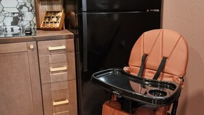 A kitchenette with a black refrigerator, wooden cabinets, and a spice rack. - Moody Maison Studio | Near Downtown & Beaches (Traverse City)