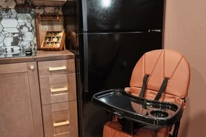 Una piccola cucina attrezzata con un frigorifero nero, mobili in legno e un ripiano per le spezie.
