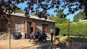 Una casa de pedra amb teulada de rajola, mobiliari exterior i zona de jardí.