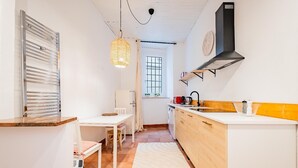 Eine kleine Küche mit Essbereich, einem weißen Kühlschrank, einer Spüle und einer Pendelleuchte.