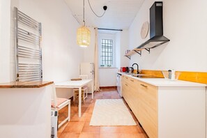 A compact kitchen with a dining area, a white refrigerator, a sink, and a hanging light fixture. - Apartment house "Iulia"- Pinerolo (historic center) (Pinerolo)