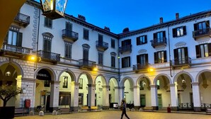 Un patio con piso de adoquines y un edificio con varios balcones y arcos de entrada.