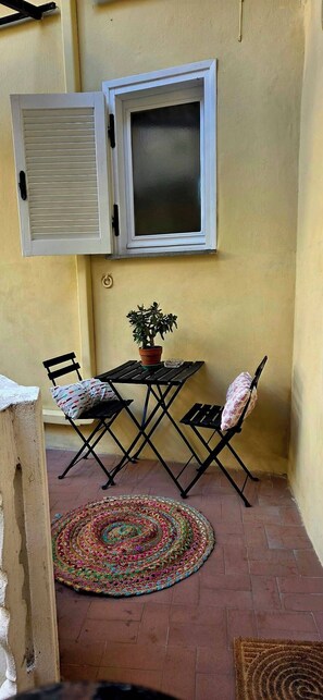 A small patio with a table and chairs, a potted plant, and a window with shutters. - Apartment house "Iulia"- Pinerolo (historic center) (Pinerolo)
