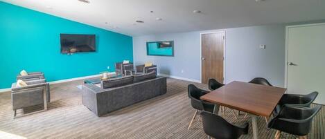 Una sala de estar moderna con un sofá grande, una mesa de centro y una zona de comedor con una mesa y sillas de madera.