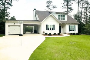 Une maison à deux étages avec un garage, une allée couverte et une pelouse bien entretenue.