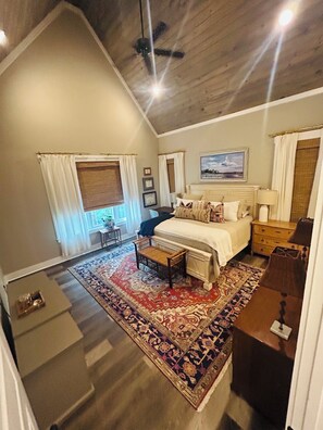 A bedroom with a bed, a nightstand, a lamp, a ceiling fan, and a window with curtains. - Family-friendly Lakefront Retreat in Peaceful Slough on beautiful Lake Martin (Dadeville)