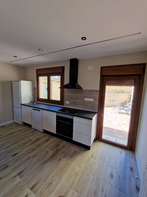 Een moderne keuken met een inbouwoven, een vaatwasser en een zwarte afzuigkap.