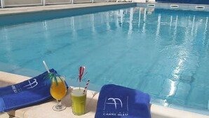 A poolside area with a towel, a glass of yellow drink, and a glass with a straw and a red and white striped straw. - Vendée getaway: Mobil home _ Commequiers (Commequiers)