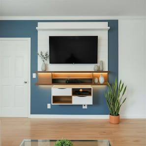 Ein Wohnzimmer mit Wand-Fernseher, Holzregalen, einem weißen Schrank und einem Topfpflanzen.
