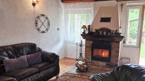 A cozy living room with a fireplace, leather sofas, and a stone coffee table. - Lakeside Holiday Villa, Private Garden (Szczecinek)