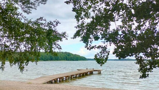 A wooden pier extending into calm water, surrounded by trees. - Lakeside Holiday Villa, Private Garden (Szczecinek)