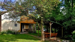 A house with a porch, a table, and a bench in a garden. - Lakeside Holiday Villa, Private Garden (Szczecinek)