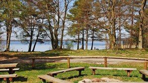 A lakeside park with picnic tables and a wooden fence. - Lakeside Holiday Villa, Private Garden (Szczecinek)