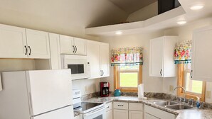 A kitchen with white cabinets, a microwave, a coffee maker, and a sink. - Spacious Cottage 4 with Loft, Full Kitchen & Stunning Views (Lake Andes)