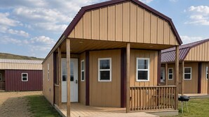 A single-story building with a covered porch and a picnic table in front. - Spacious Cottage 4 with Loft, Full Kitchen & Stunning Views (Lake Andes)