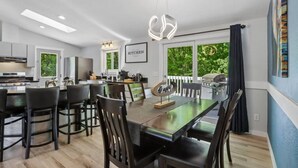 A modern kitchen with a dining area, large windows, and a view of greenery. - Arbor House - A House for Families & Friends (Lyndon Station)