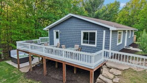A two-story house with a deck, a hot tub, and a stone retaining wall. - Arbor House - A House for Families & Friends (Lyndon Station)