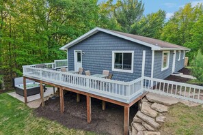 A two-story house with a deck, a hot tub, and a stone retaining wall. - Arbor House - A House for Families & Friends (Lyndon Station)