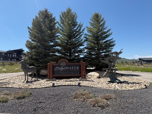 A sign with 'Edgewater' and 'The Chalets' written on it, surrounded by trees and a sculpture of a deer. - Meadowlark Nest CEW1 | Hot Tub | Swim Spa |Game Rm (Huntsville)