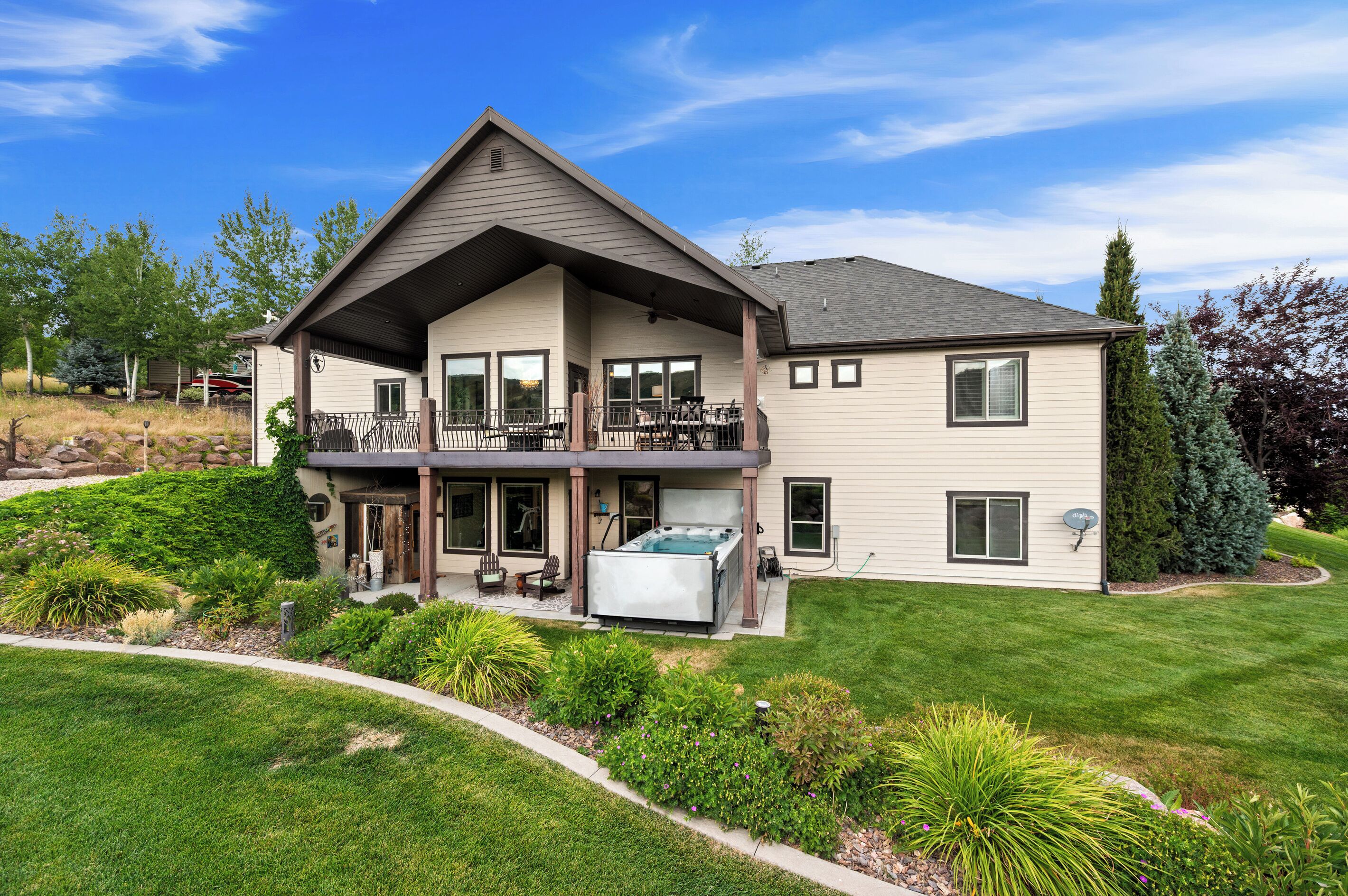 A two-story house with a covered patio, a hot tub, and a well-maintained lawn.