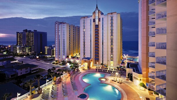 Ein Hotel mit mehreren Hochhäusern, einem Swimmingpool und Blick auf den Strand.