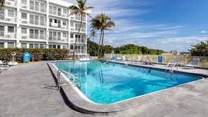 A rectangular pool with a tiled edge, surrounded by lounge chairs and a white fence. - Pompano Beach Family Getaway with Pools & Spacious 2BR Retreat (Pompano Beach)