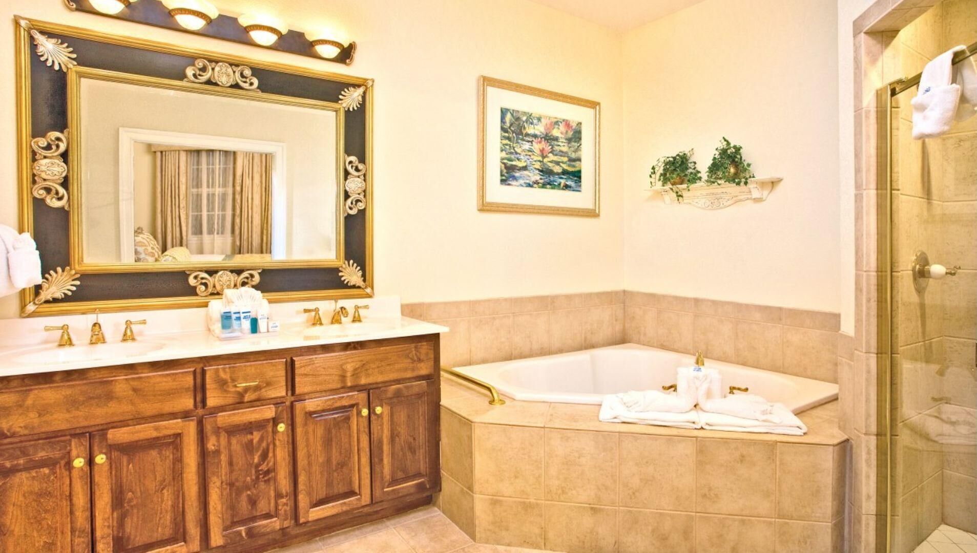 Une salle de bain dotée d’un grand miroir, d’une baignoire, de meubles en bois et d’un espace douche.