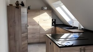 Una cocina moderna con armarios de madera, encimera negra y tragaluz.