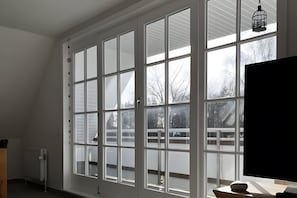 A room with large windows, a radiator, and a TV.