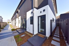 A modern residential building with a clean, geometric design, featuring a narrow driveway and a gated entrance. - Contemporary City Stay with Wellness Access (Christchurch)