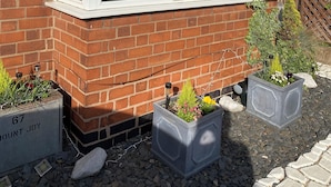 A house with a bay window, brick walls, and two flower planters labeled '67 Mount Joy.' - Cosy Cottage style Bungalow Close to Leicester City, Abbey Park & The Highcross (Leicester)