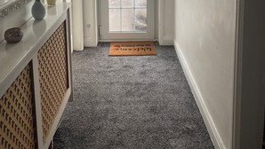 A hallway with a frosted glass door, a fire exit sign, a welcome mat, and a mirror with decorative items. - Cosy Cottage style Bungalow Close to Leicester City, Abbey Park & The Highcross (Leicester)