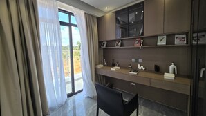 A modern room with a desk, chair, and large windows with curtains.