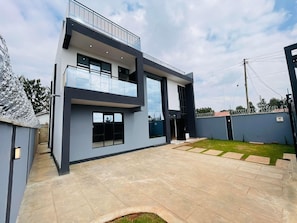 Ein modernes, zweistöckiges Haus mit Balkon, Garage und gepflegtem Rasen.