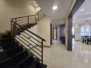 Ein modernes Interieur mit einer schwarzen Treppe, einem Essbereich und einem Flur zu einem weiteren Raum.