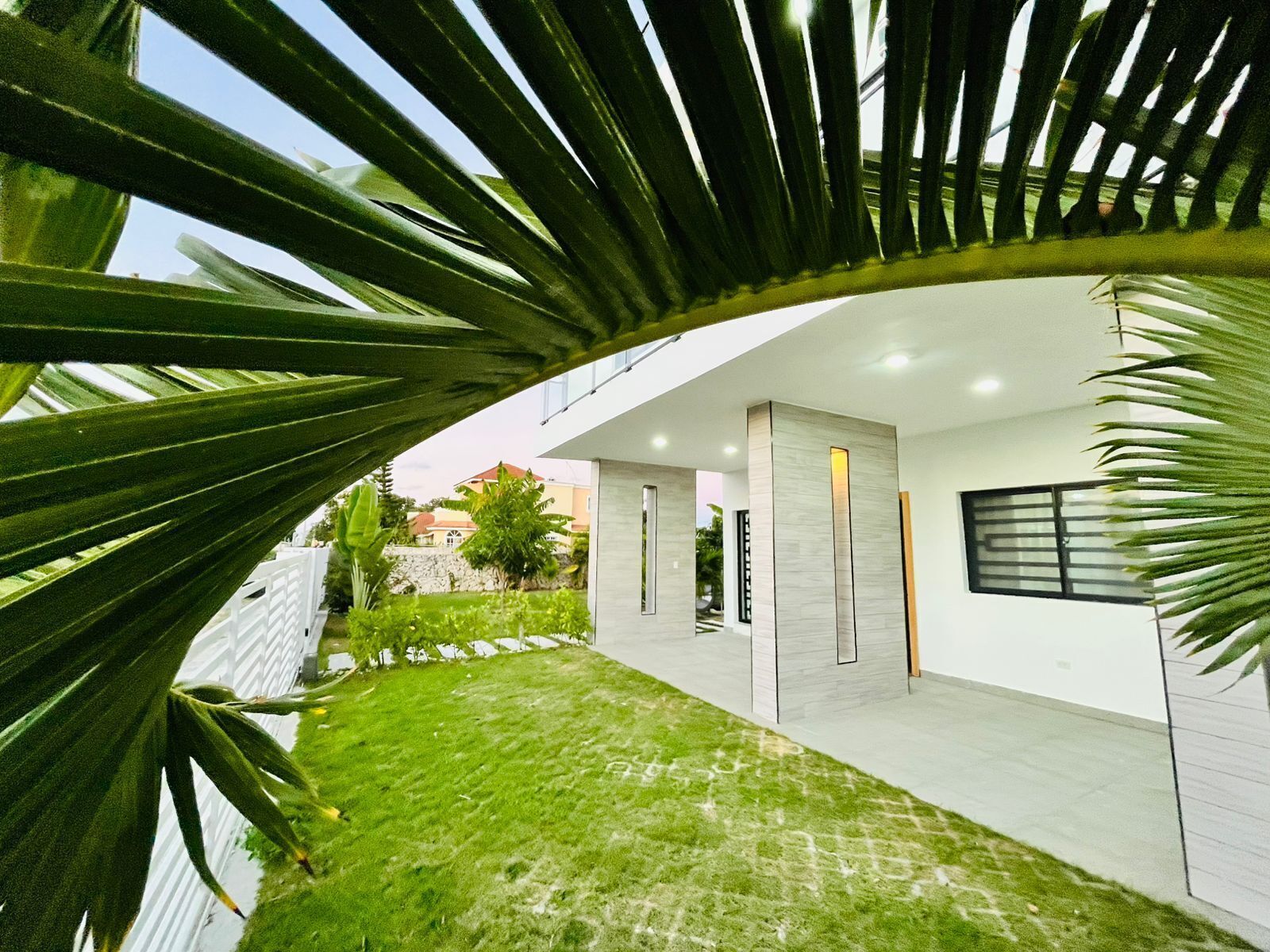 A modern building with a flat roof, a paved courtyard, and a white exterior wall.