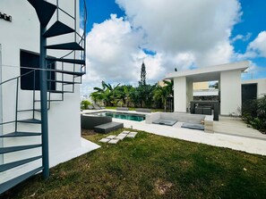 Ein moderner Außenpoolbereich mit Treppe, Sitzgelegenheiten und Blick zum Himmel.