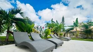 A poolside area with wicker lounge chairs and a stone wall.