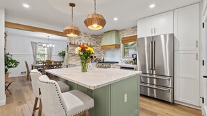 A modern kitchen with a central island, stainless steel appliances, and a dining area with wooden chairs.
