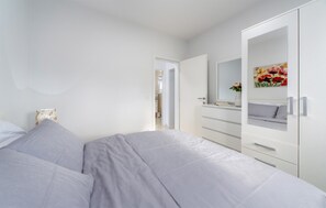 Ein Schlafzimmer mit einem Bett, einem Kleiderschrank, einem Spiegel und einem Gemälde.