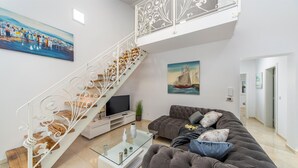 Una sala de estar moderna con una escalera, un sofá, un televisor y obras de arte en las paredes.