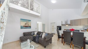 Una sala de estar moderna con un sofá gris, una mesa de centro de vidrio y un comedor con una mesa y sillas.