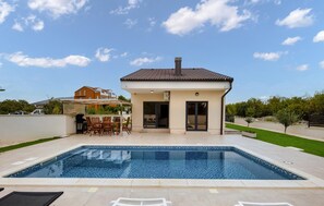 A modern house with a swimming pool, patio furniture, and a clear sky. - Lovely home in Bilice (Bilice)