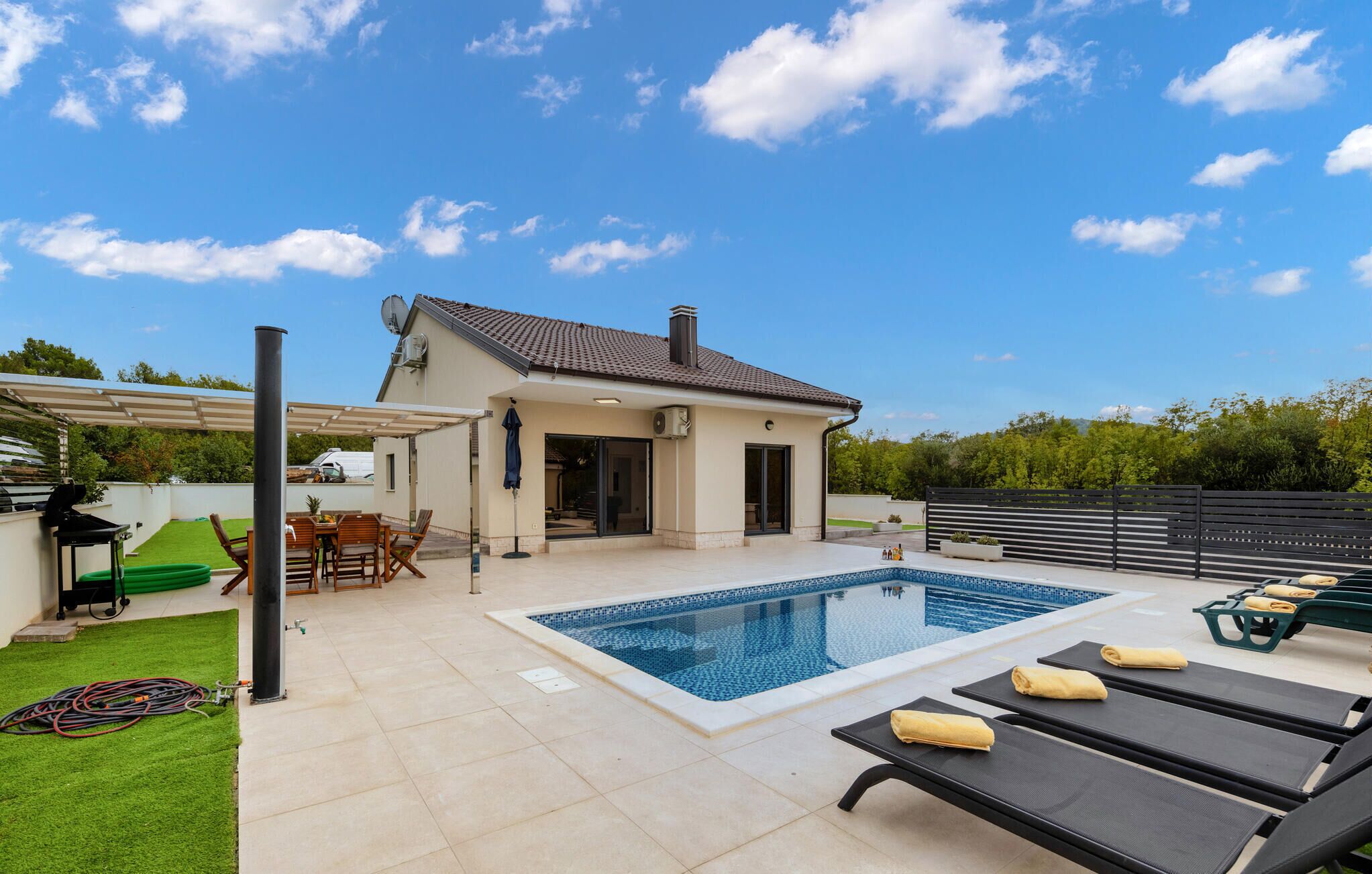 Ein Haus mit Swimmingpool, Außenbereich mit Sitzgelegenheiten und einer überdachten Terrasse.